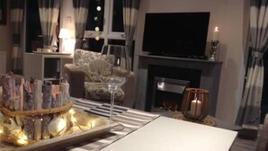 En hyggelig stue med pejs, et fladskærms-tv og en spiseplads med et glasbord.