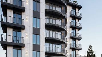 Un hotel moderno de varios pisos con balcones, área de estacionamiento y fachada bien conservada.