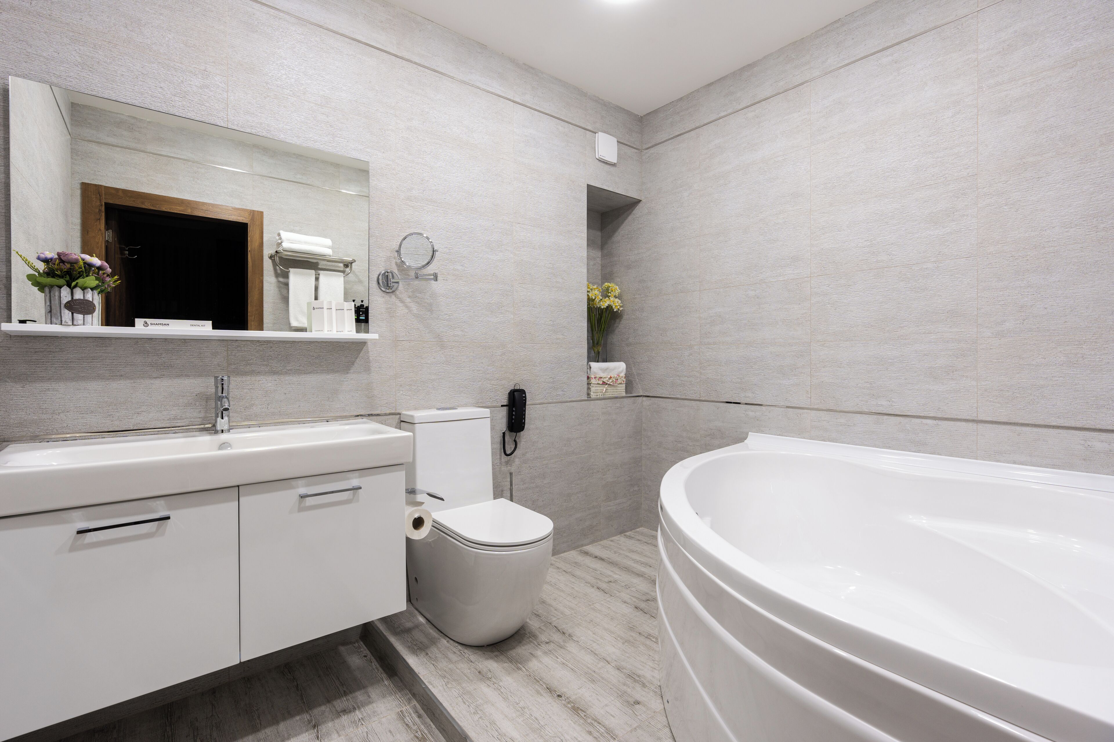 Un bagno moderno con un mobile lavabo bianco, un water, una vasca da bagno e uno specchio.