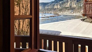 Une pièce avec une fenêtre donnant sur un paysage enneigé et une rivière.