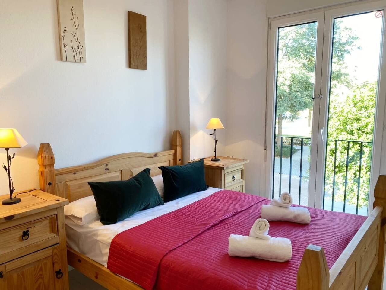 Quarto de hotel com cama, duas mesas de cabeceira, janela com vista e varanda.
