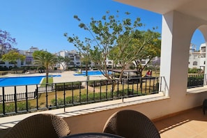 A balcony with a view of a swimming pool, a playground, and surrounding buildings. - A bright pool views apartment - CO1011LT (Torre-Pacheco)