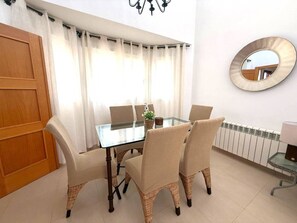 A dining area with a glass table, six chairs, a potted plant, and a round mirror on the wall. - Villa with private pool - CA13LT (La Torre Golf Resort)