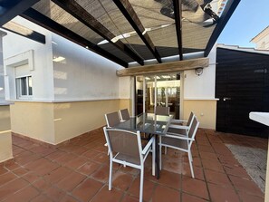An outdoor patio with a glass-top table and chairs, surrounded by a tiled floor and a pergola structure. - Villa with private pool - CA13LT (La Torre Golf Resort)