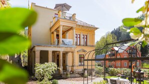 A two-story building with a balcony and a garden area. - Modern apartment 1 in Villa Emma for 2-4 people (Bad Schandau)