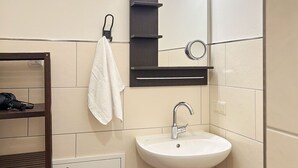 A compact bathroom with a white sink, a mirror, and a towel hanging on a rack. - Modern apartment 1 in Villa Emma for 2-4 people (Bad Schandau)