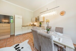 Een moderne keuken met witte kasten, een ingebouwde kookplaat en een eethoek met een tafel gedekt voor twee personen.