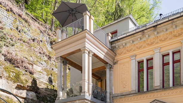 A two-story building with a balcony, columns, and a door with a window.