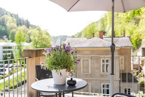 A balcony with a table, a potted plant with purple flowers, and a butterfly decoration. - Modern Vacation Apartment 5 (Studio) at Villa Emma for 2 people (Bad Schandau)