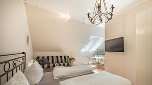 A bedroom with a bed, a sofa, a TV, and a chandelier.