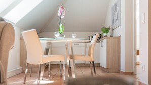 A dining area with a table, chairs, and a vase with flowers.
