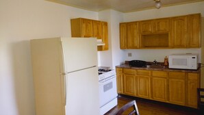 Una cocina con armarios de madera, un refrigerador blanco, una estufa y un microondas.