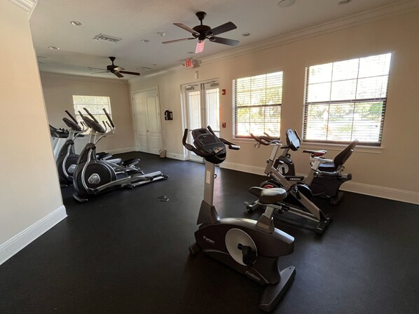 A gym with stationary bikes, treadmills, and a ceiling fan.
