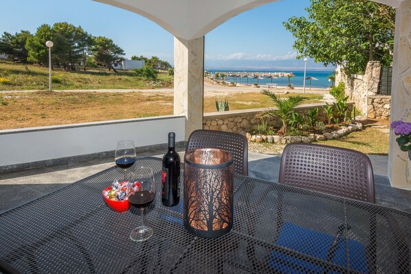 A table with a bottle of wine, a glass, and a decorative candle. - Apartments Andelic (Vir)
