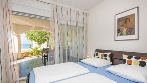 A hotel room with two beds, a view of the ocean, and a painting on the wall. - Apartments Andelic (Vir)