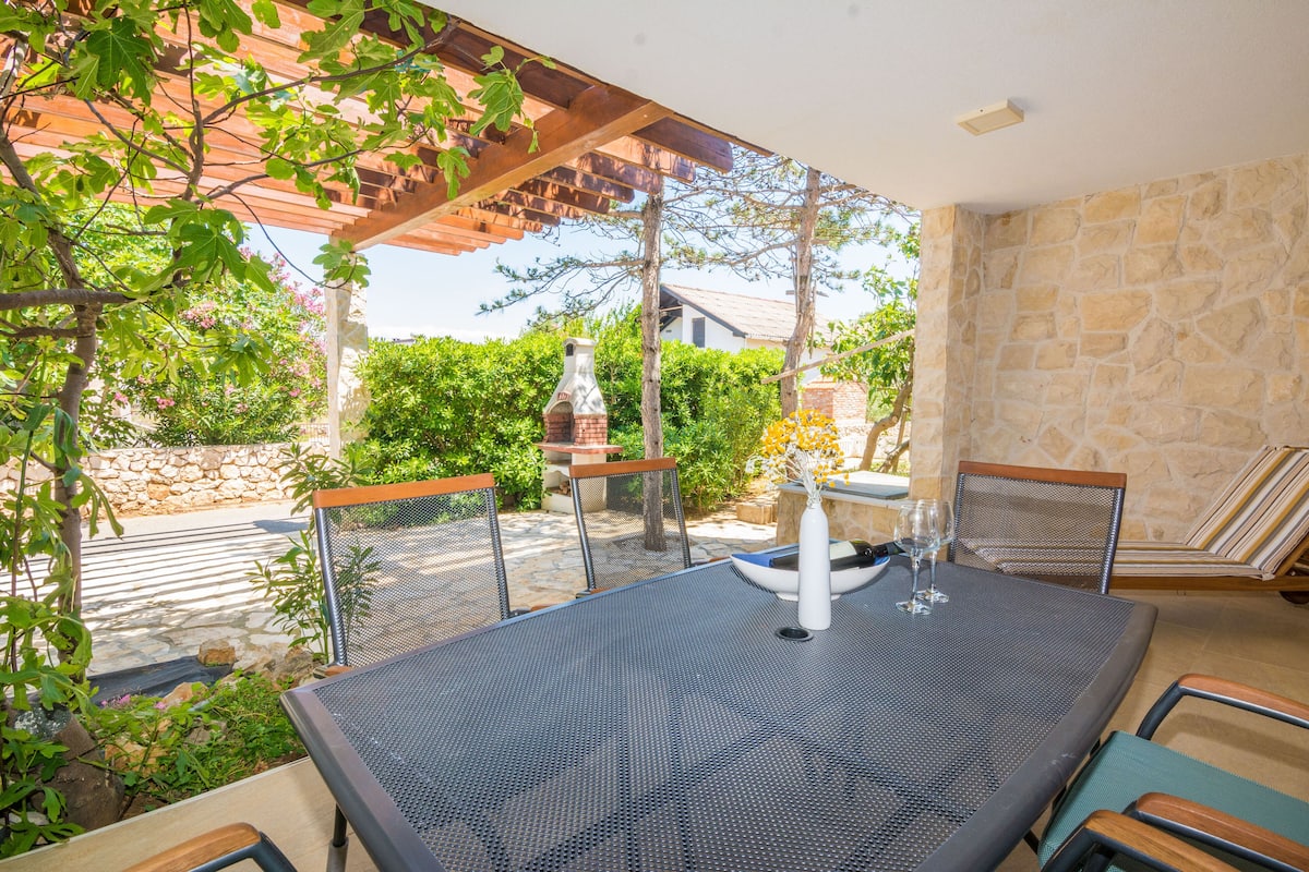 An outdoor patio with a table and chairs, a pergola, and a stone wall.