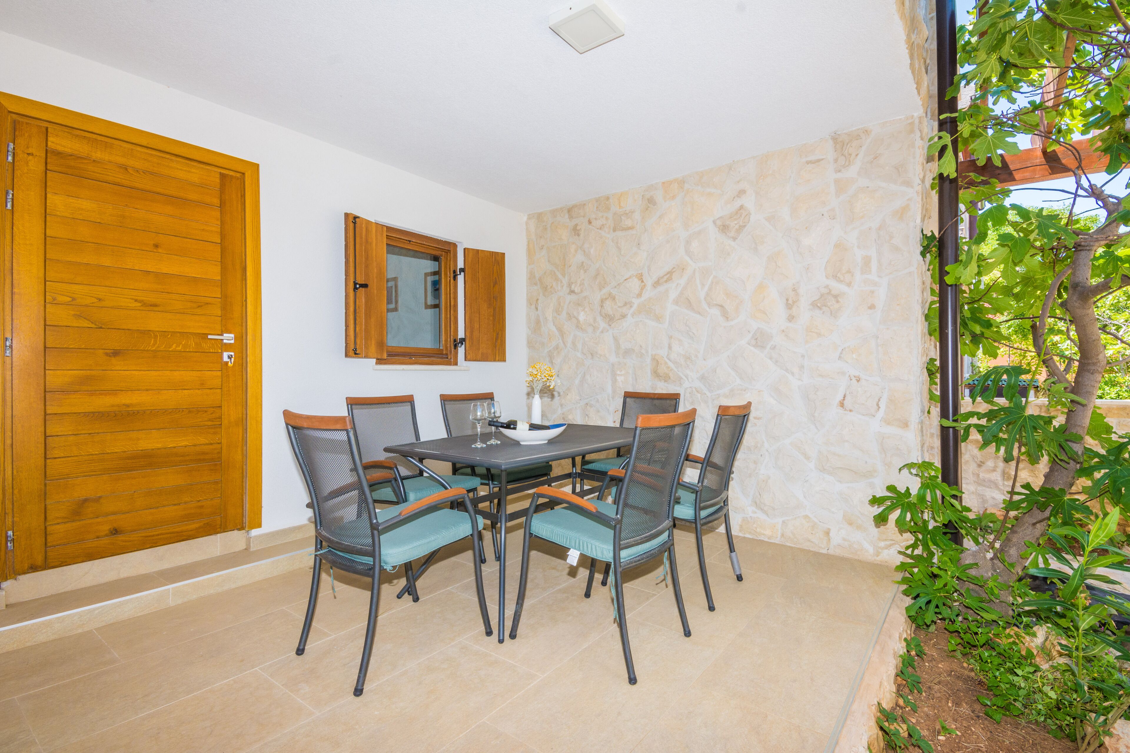 A dining area with a stone wall, a wooden door, and a window with a wooden frame.