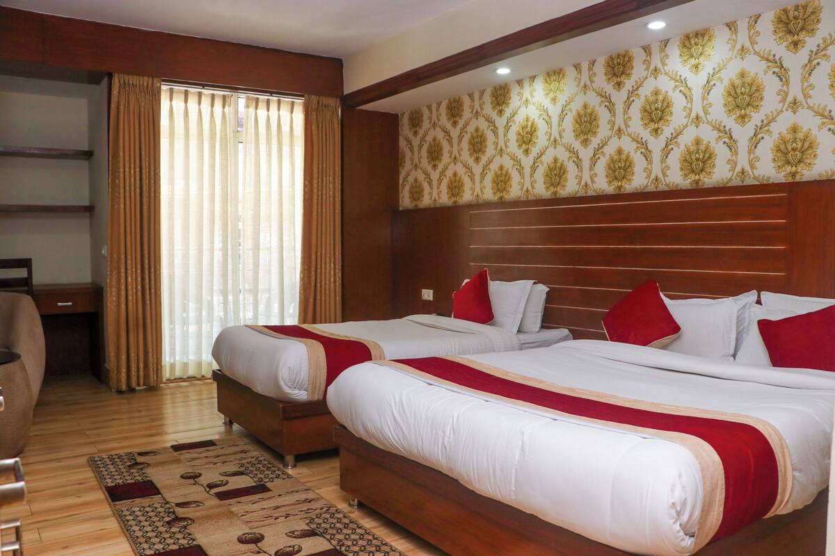 Une chambre d’hôtel avec deux lits, une tête de lit en bois, un bureau et une chaise.
