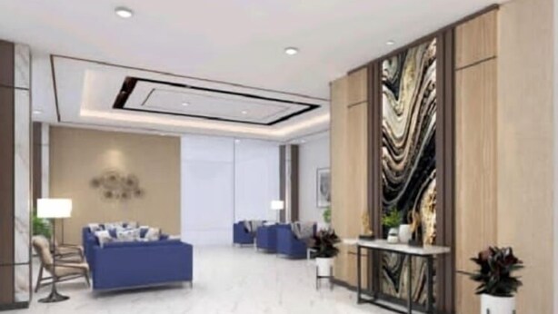 A modern hotel lobby with a seating area, a reception desk, and a decorative wall.