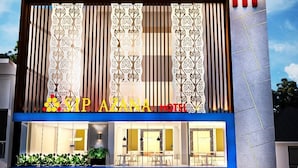 A modern hotel facade with a prominent vertical design, a flag, and a staircase leading to the entrance.