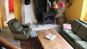 A cozy living room with a fireplace, a green armchair, a wooden coffee table, and a green sofa. - GÎTE DE LA COLLINE AUX FRAMBOISES (Oloron-Sainte-Marie)