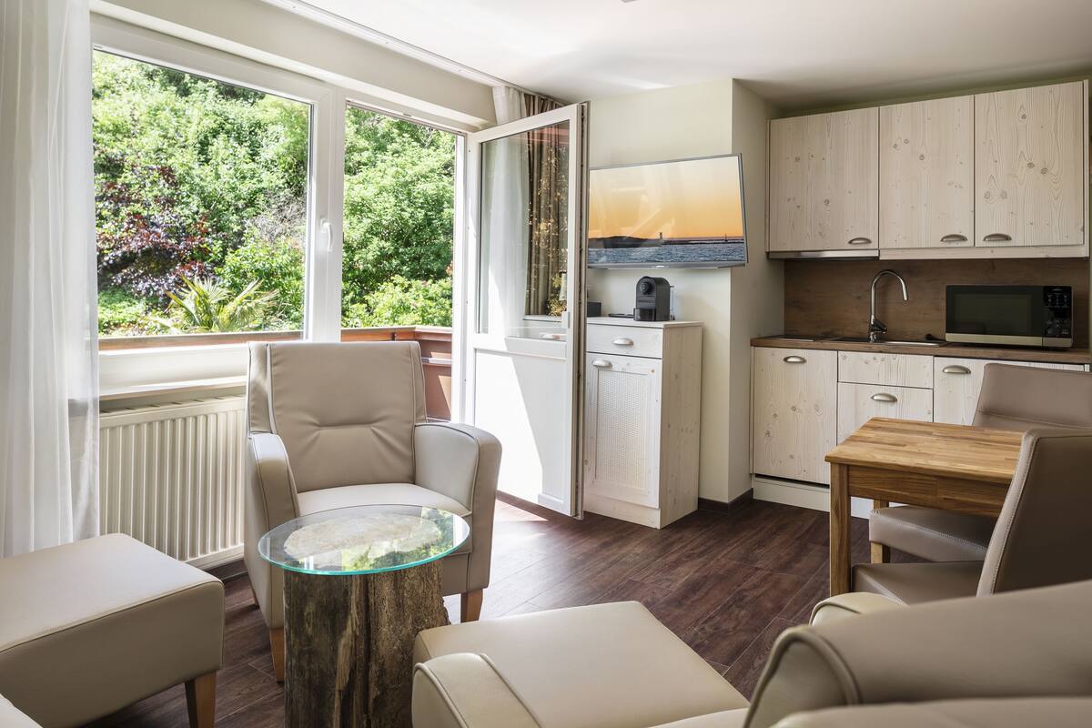 Una cucina moderna con zona pranzo, un'ampia finestra vista su spazi verdi e TV a incasso.