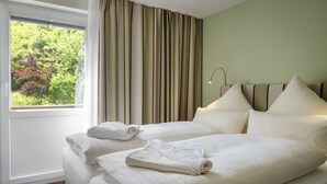 Ein Hotelzimmer mit zwei Betten, einem großen Fenster und Vorhängen.