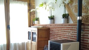 Una cocina con estufa de leña, suelo de baldosas y pared de ladrillo.