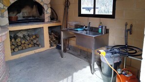 Una chimenea de piedra, un lavamanos y una ventana en una cocina rústica.