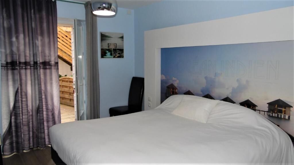 A hotel room with a bed, a desk, and a large window.
