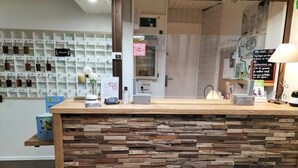 A reception desk with a stone-textured counter, a wall-mounted display of keycards, and a sign with QR code. - HOTEL RESTAURANT HERARD  (Bourbonne-les-Bains)
