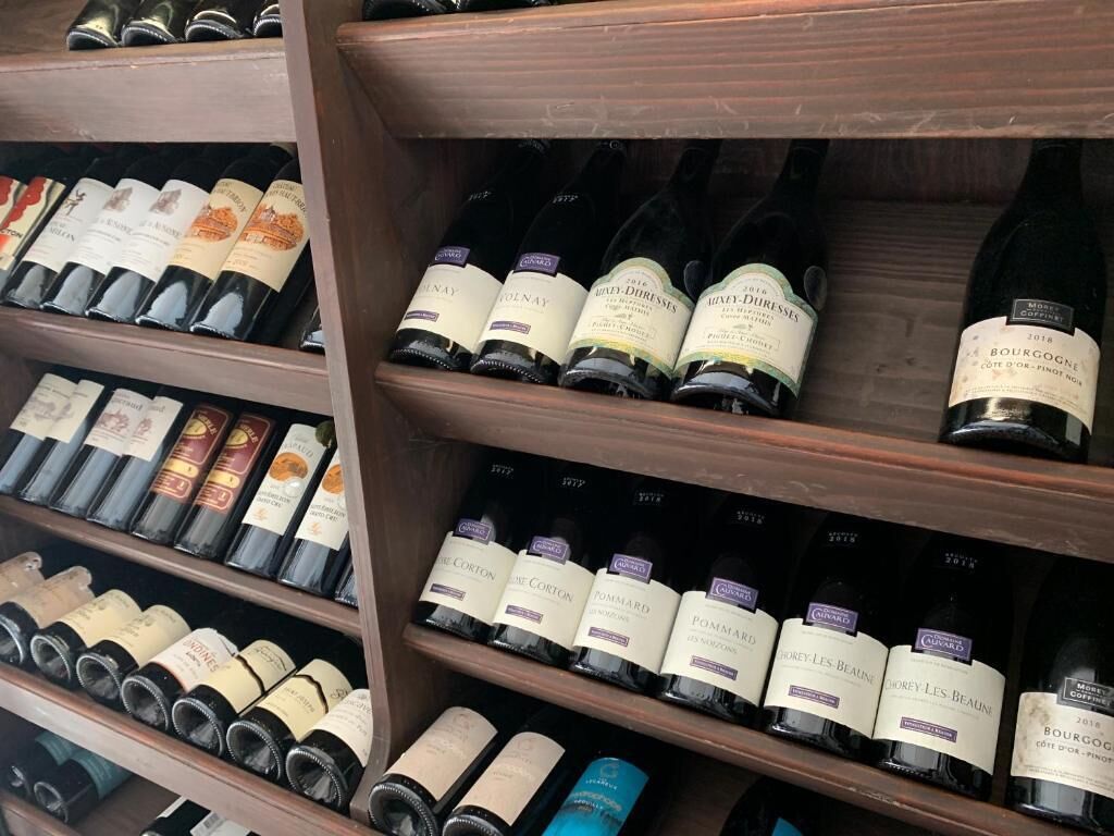 A wine rack with various bottles of wine, including brands like Pommard and Coton.