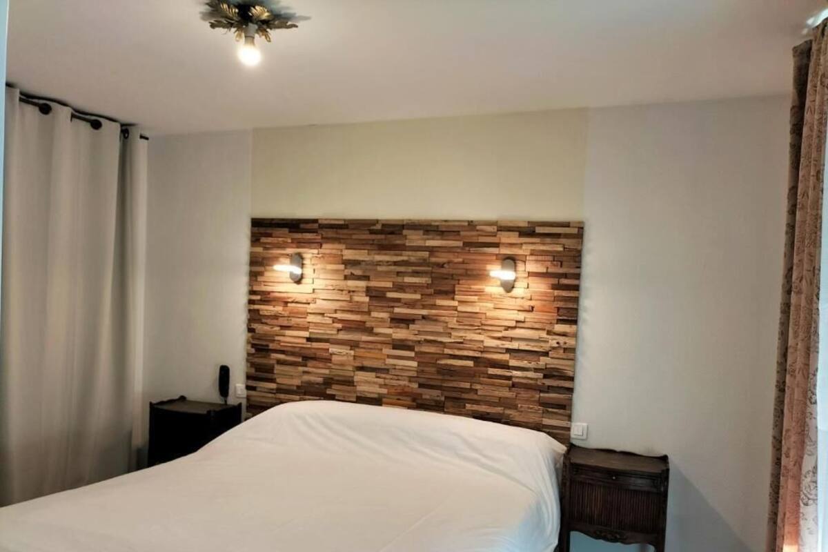 A bedroom with a wooden headboard, a bed, a nightstand, and a bedside table.