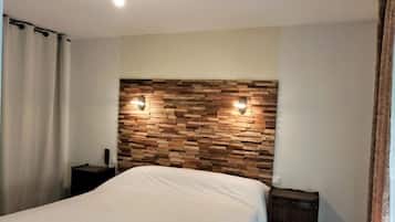 Un dormitorio con cabecera de madera, una cama, una mesita de noche y una mesita auxiliar.
