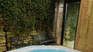 A hot tub with a wooden deck and a stone wall with greenery behind it. - HOTEL RESTAURANT HERARD  (Bourbonne-les-Bains)