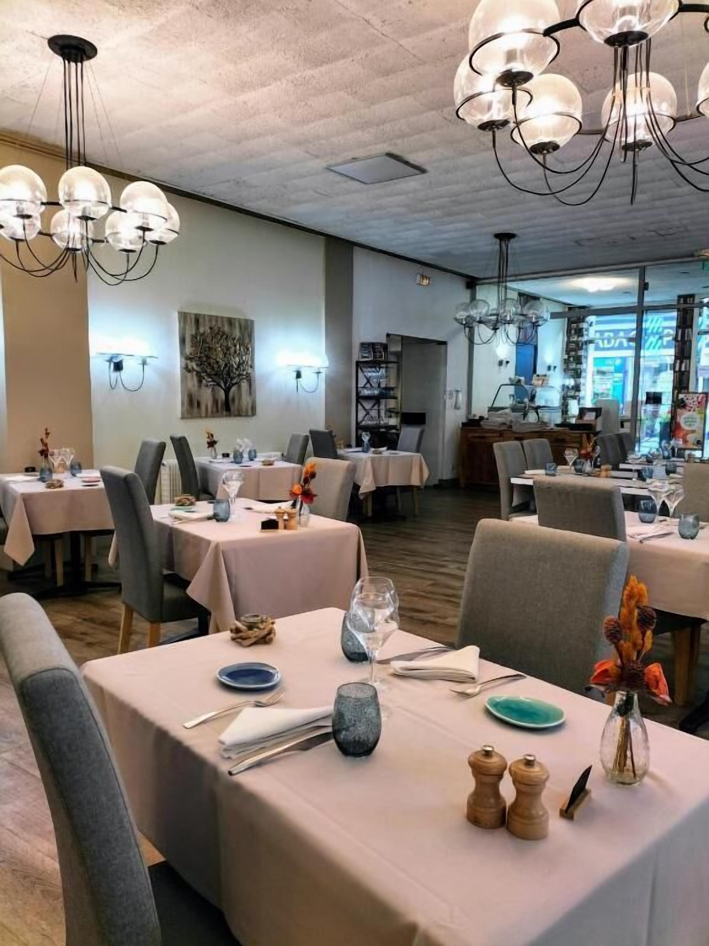 Een restaurant met meerdere tafels, elk gedekt met borden, bestek en glazen.
