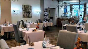 Een restaurant met meerdere tafels, elk gedekt met borden, bestek en glazen.
