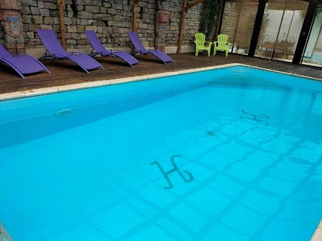 Una piscina con sillas de descanso y un muro de piedra al fondo.