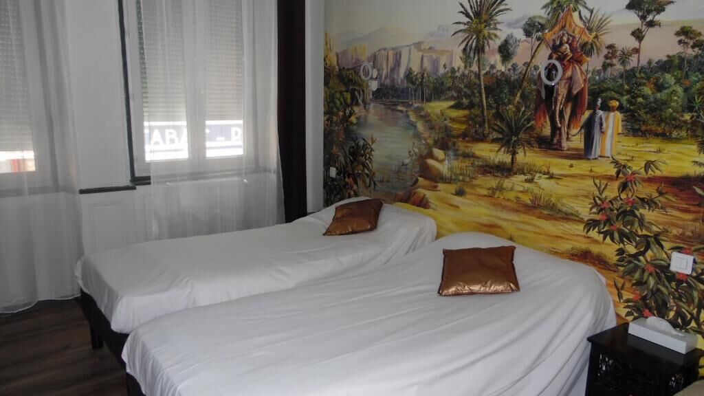 Habitación de hotel con dos camas, ropa blanca y almohadas marrones. En la pared, un mural muestra una escena tropical.