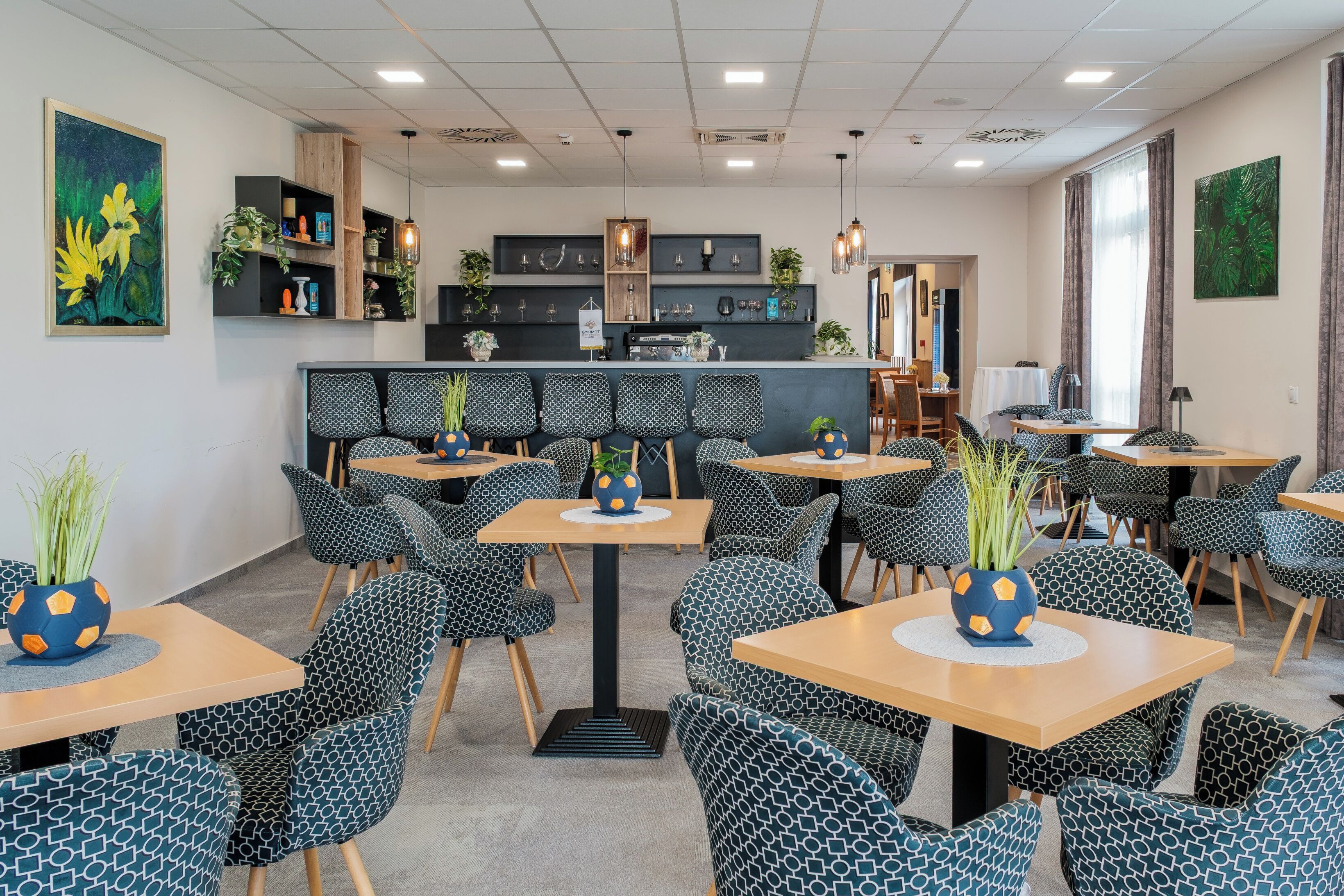 A modern hotel lobby with a bar area, seating arrangements, and artwork on the walls.