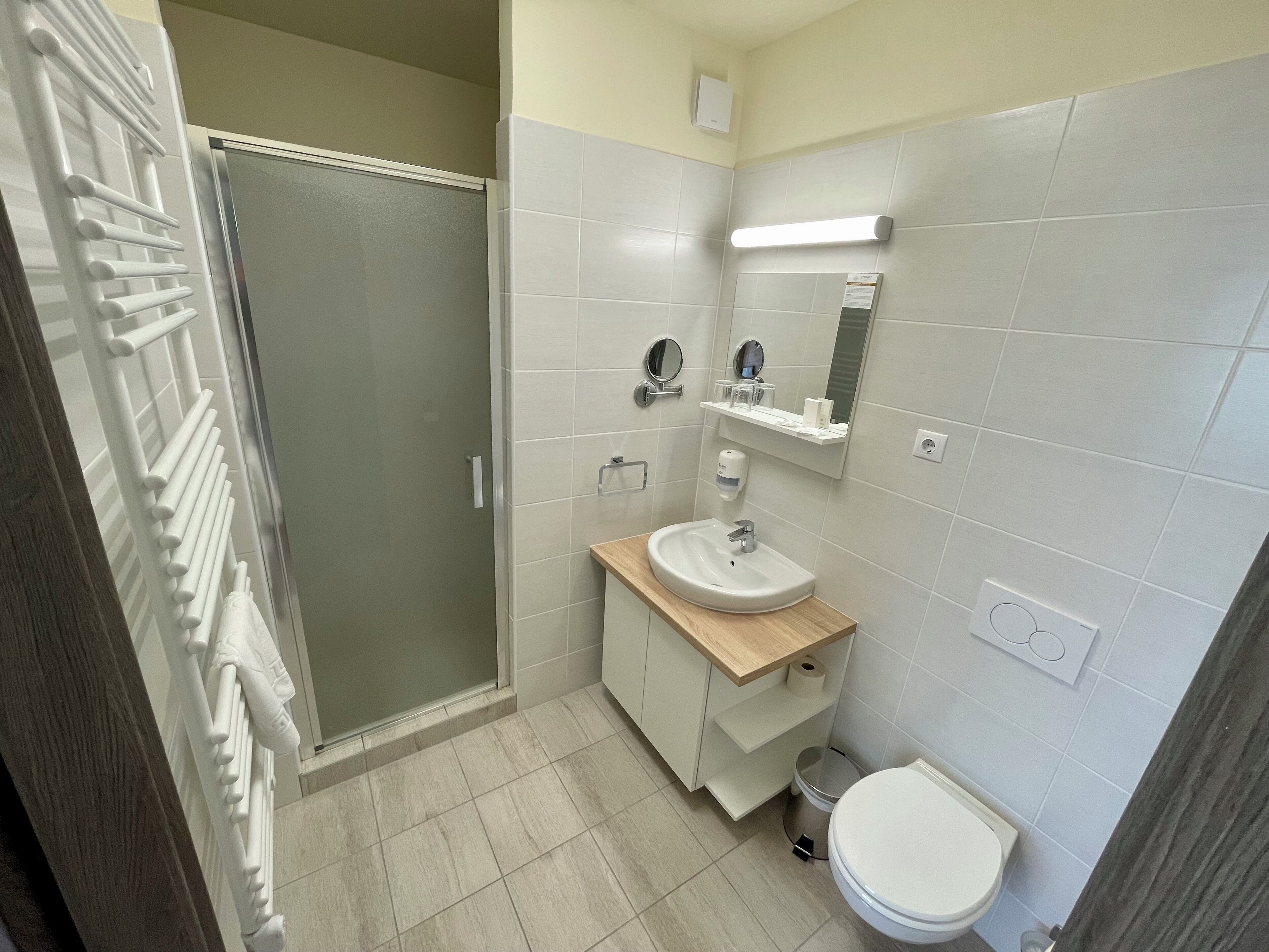 Une salle de bain équipée d’une douche, de toilettes, d’un lavabo et d’un miroir.