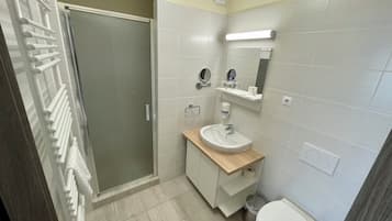 A bathroom with a shower, toilet, sink, and mirror.
