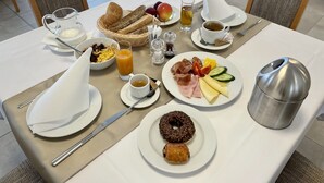 A breakfast table with plates of food, a coffee cup, a juice glass, and a thermos. - Gyirmót Sport&Wellness Hotel (Gyor)