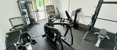 Gimnasio con equipo de ejercicio, incluyendo una bicicleta estática, caminadora y máquinas de pesas.