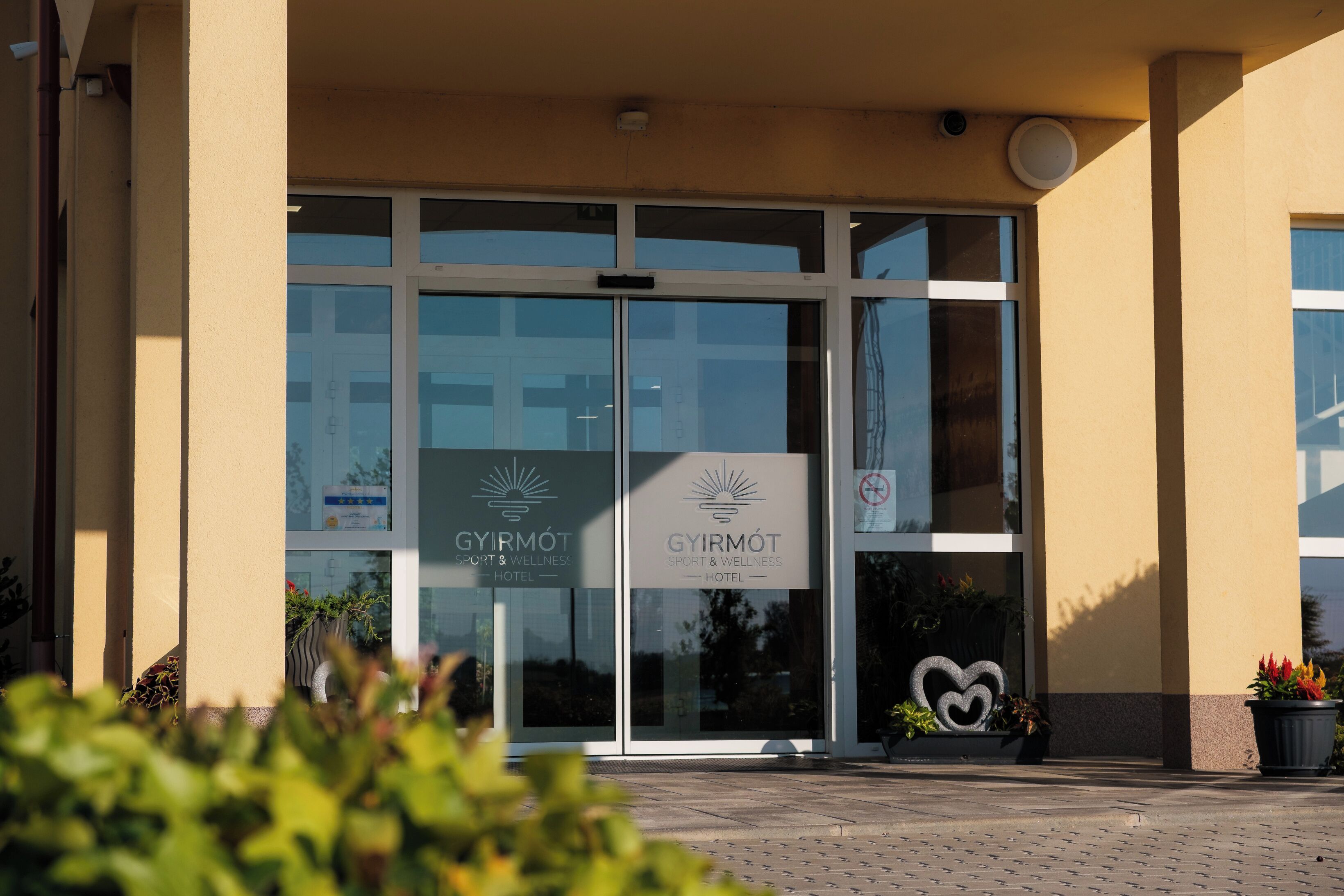 Entrada de hotel con puertas de vidrio, un logotipo y una decoración con forma de corazón.
