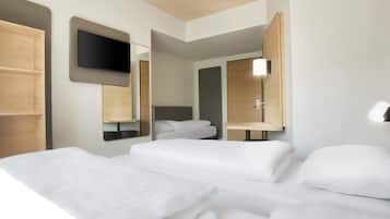 Una habitación de hotel moderna con dos camas, un televisor de pantalla plana montado en la pared y una mesita de noche con lámpara.