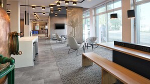 A modern office space with a reception desk, seating area, and large windows. - B&B Hotel Köln-City (Cologne)