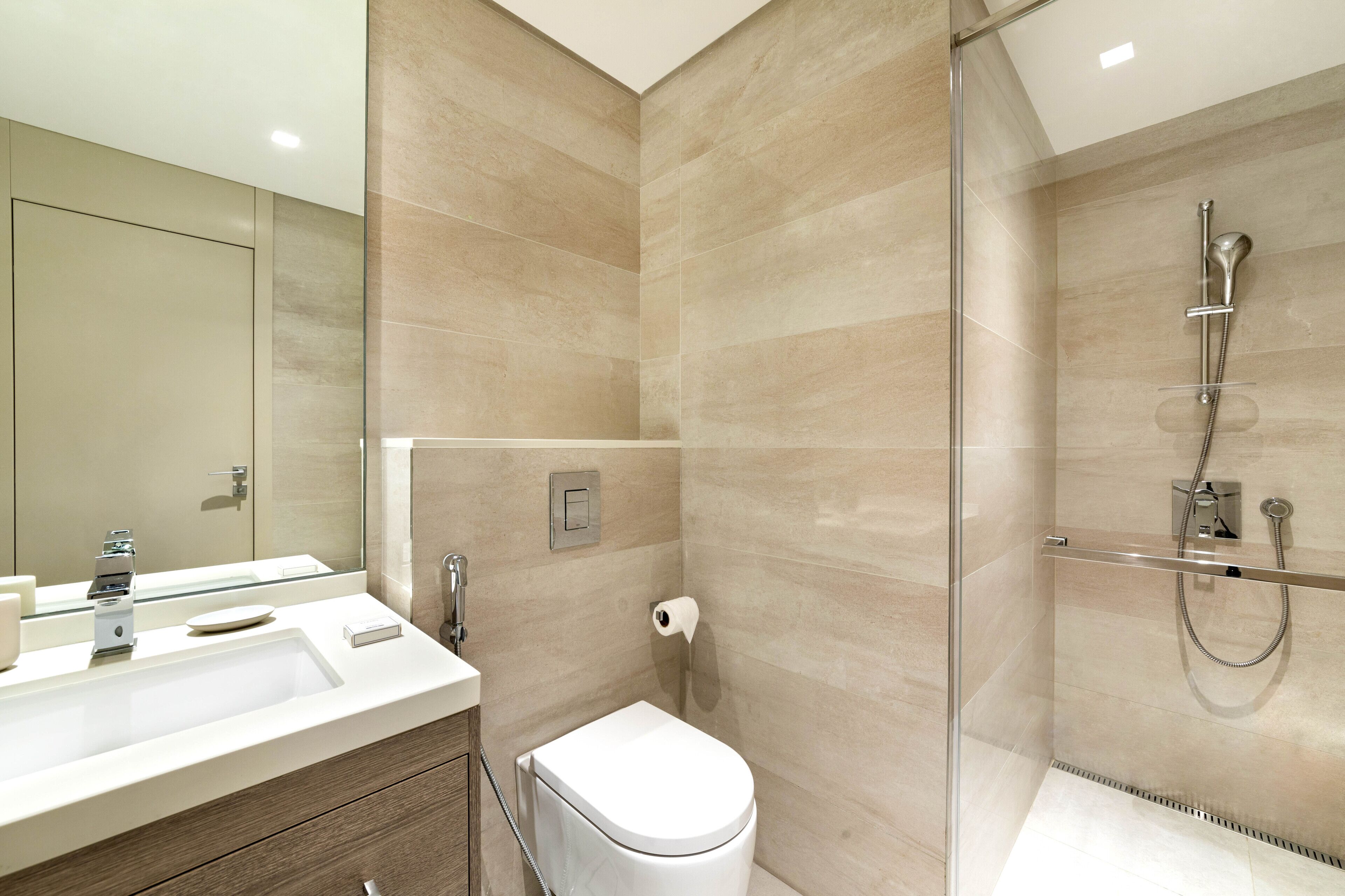 Un baño moderno con cabina de ducha de vidrio, inodoro y tocador con lavabo y espejo.