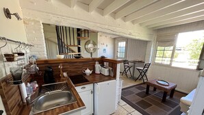 Una cocina compacta con encimera de madera, un lavamanos, un refrigerador pequeño y una zona de comedor con mesa y sillas.
