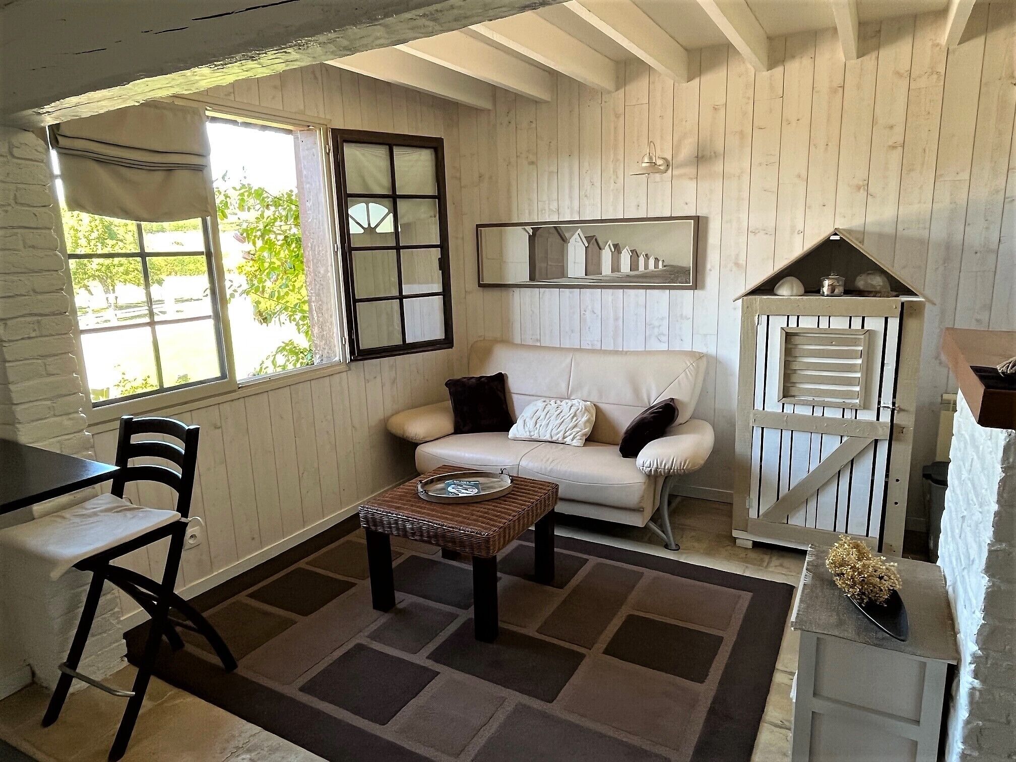 A cozy room with a white sofa, a small table, a chair, and a wooden cabinet.